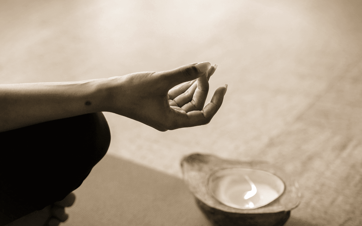Meditative Hand-Mudra mit Kerze in warmen Erdtönen
